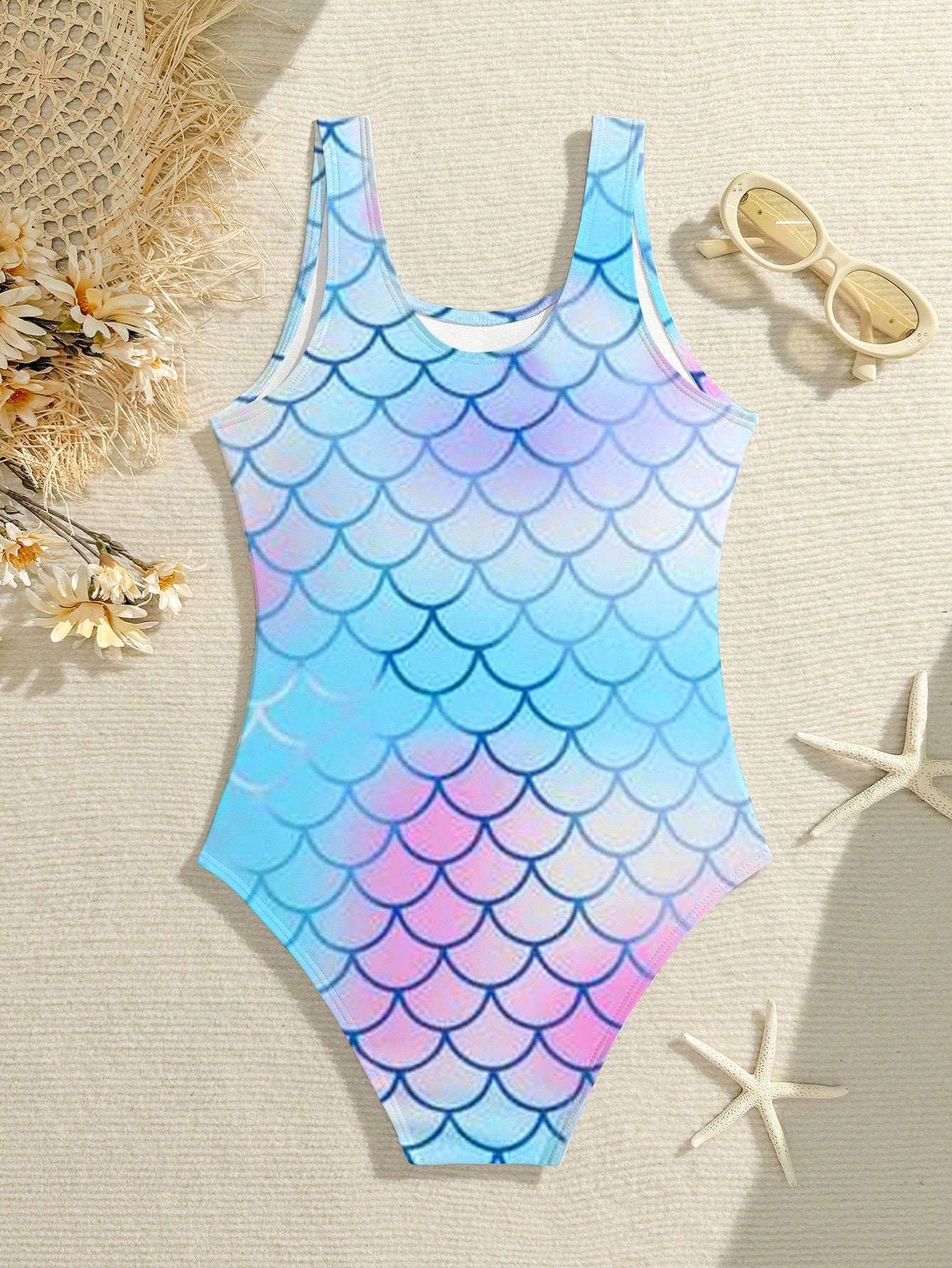 Tween girls one-piece swimsuit with a black base and multicolor tropical plant print featuring bamboo, palm leaves, plumeria flowers, scoop neck, and wide straps.