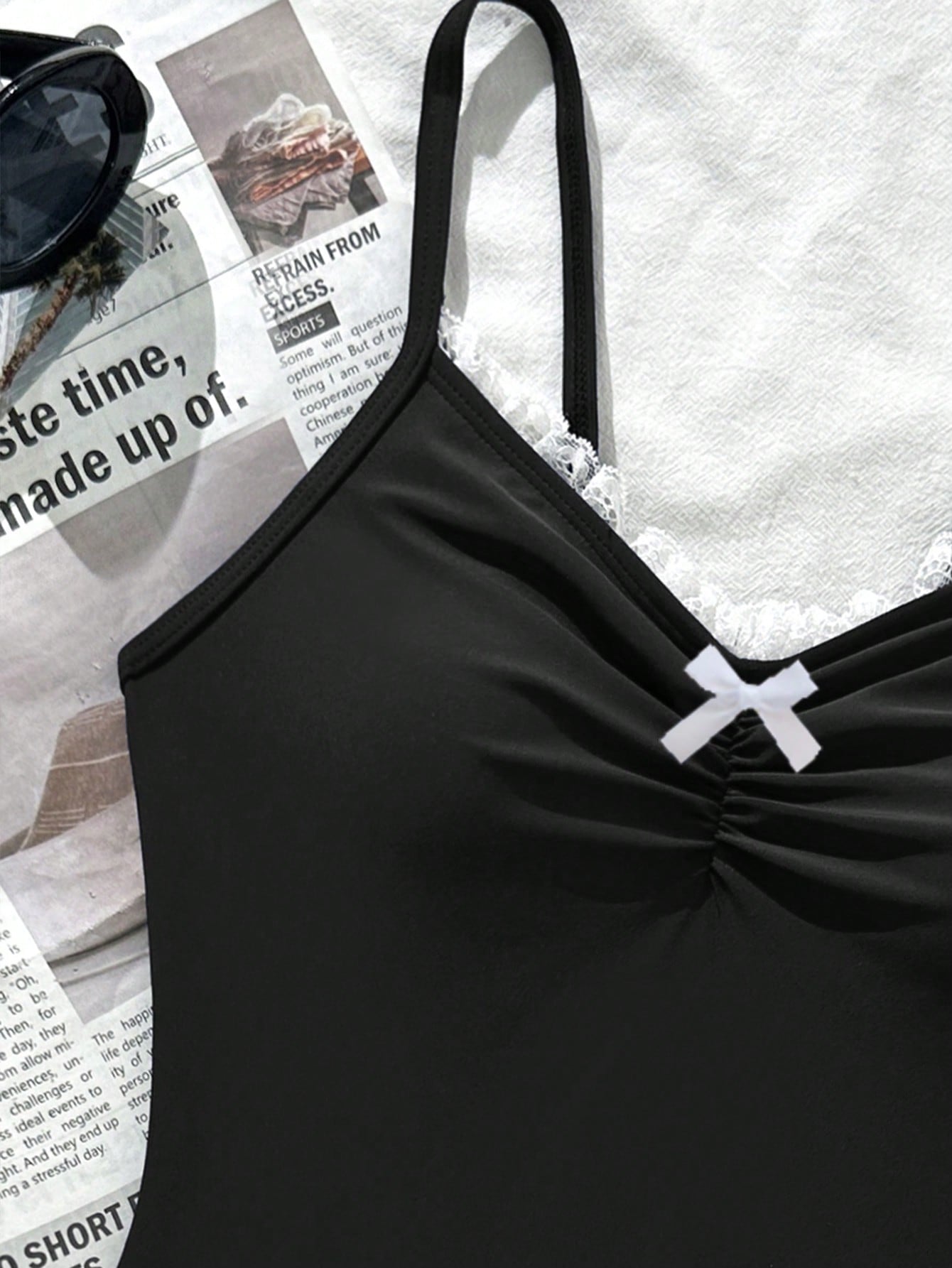 Tween girls' one-piece swimsuit featuring a ruffle splice front, ruched detailing, bow accent, contrast lace trim, and spaghetti straps.