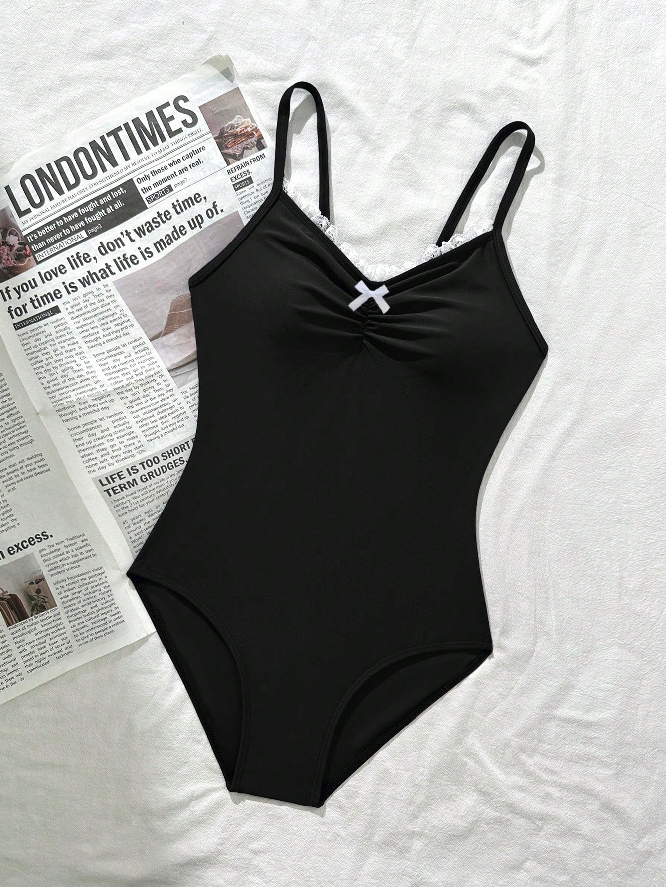 Tween girls' one-piece swimsuit featuring a ruffle splice front, ruched detailing, bow accent, contrast lace trim, and spaghetti straps.