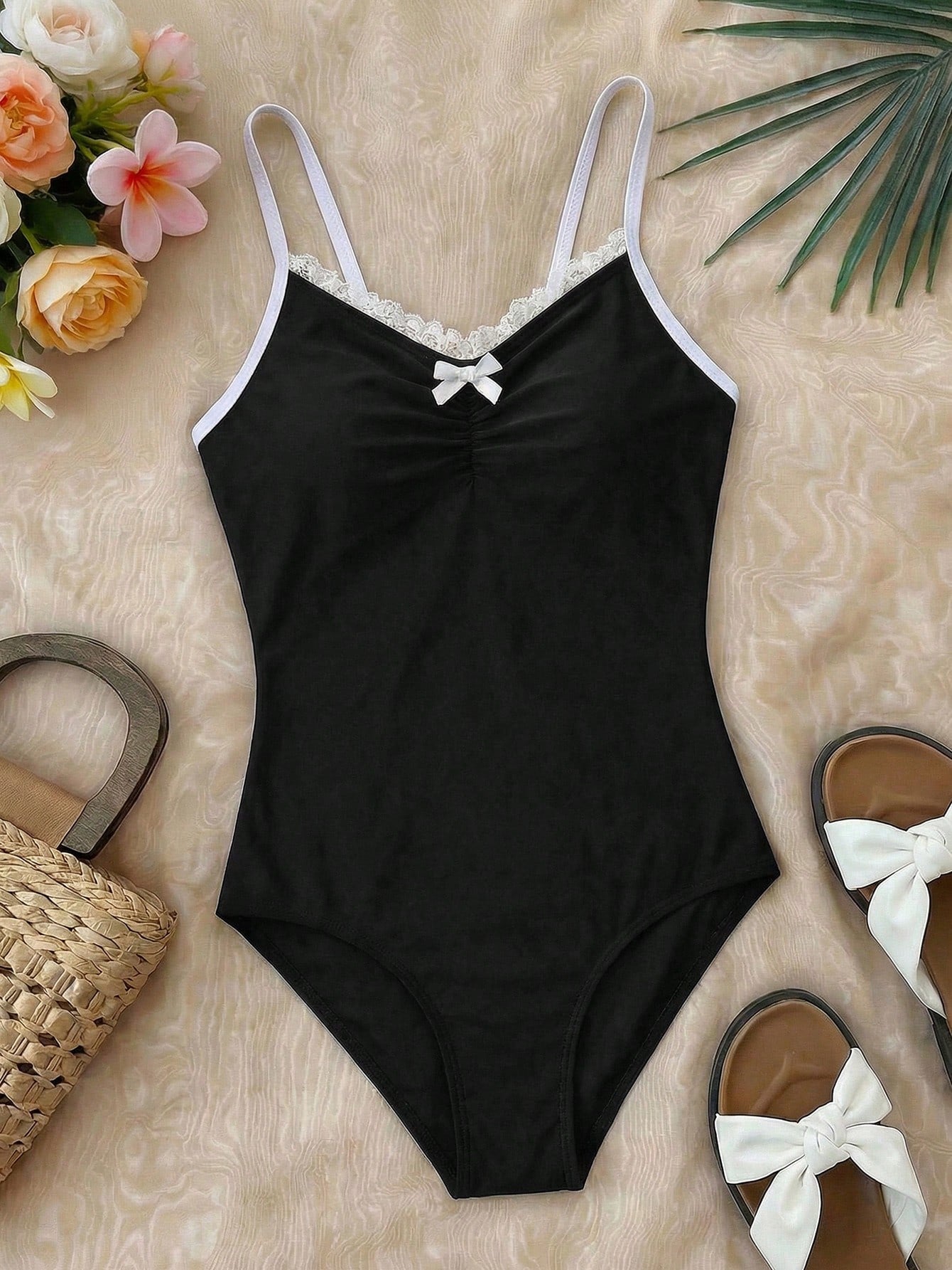 Tween girls' one-piece swimsuit featuring a ruffle splice front, ruched detailing, bow accent, contrast lace trim, and spaghetti straps.