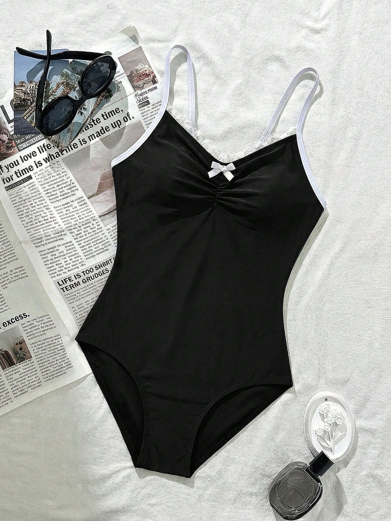 Tween girls' one-piece swimsuit featuring a ruffle splice front, ruched detailing, bow accent, contrast lace trim, and spaghetti straps.