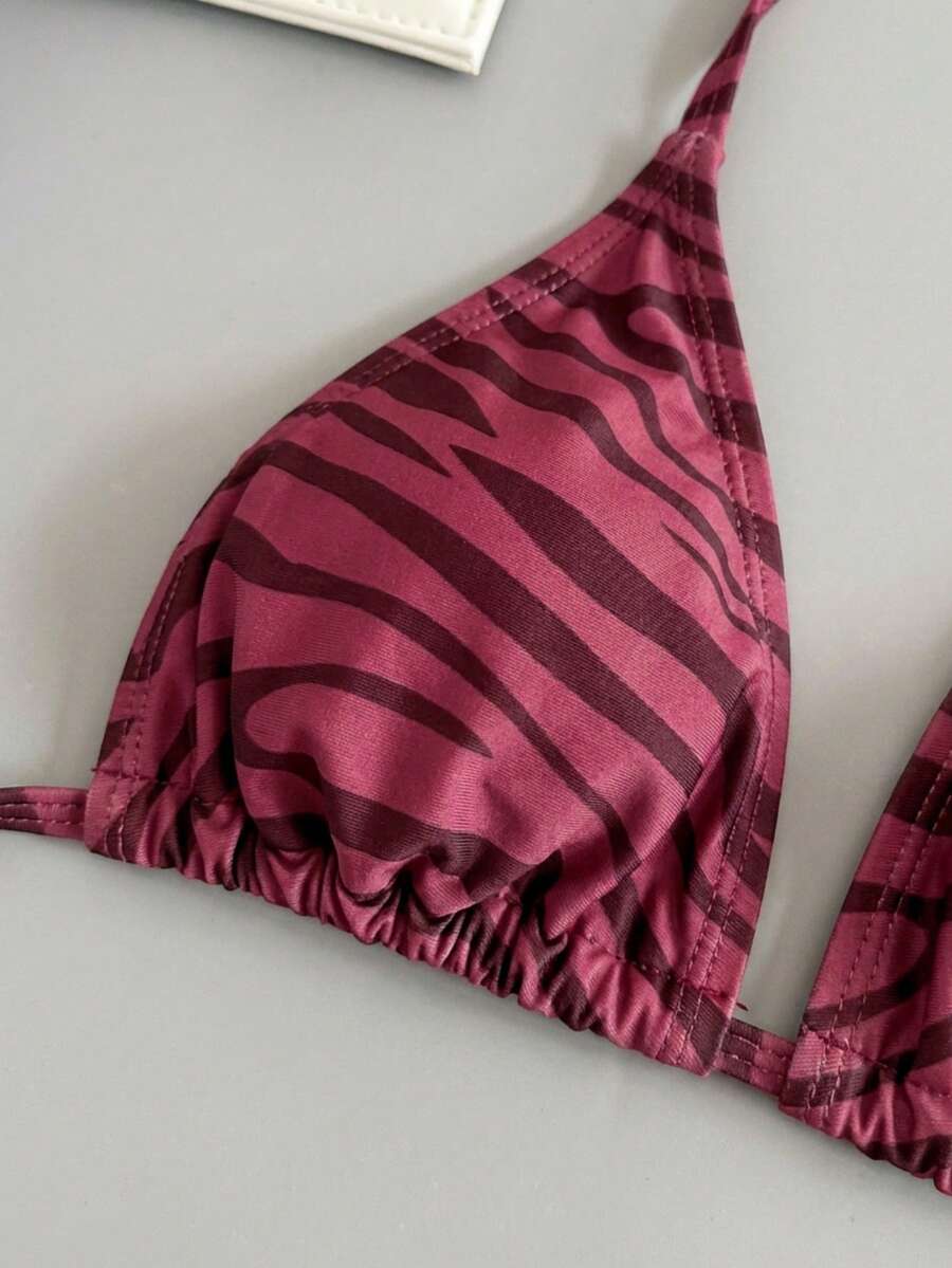 Women's black and white zebra print two-piece bikini set featuring a high waist tie-side bottom and a backless halter top with removable padding.