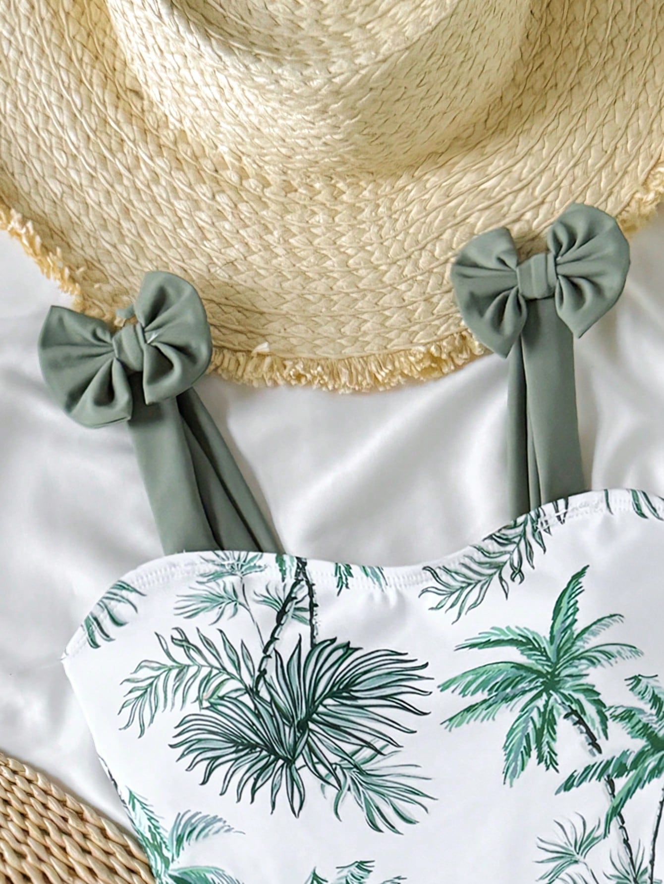 Girls' multicolor one-piece swimsuit with floral plant print, bow detail, asymmetrical ruffle accent, strap neckline, and lined body for beach vacations.