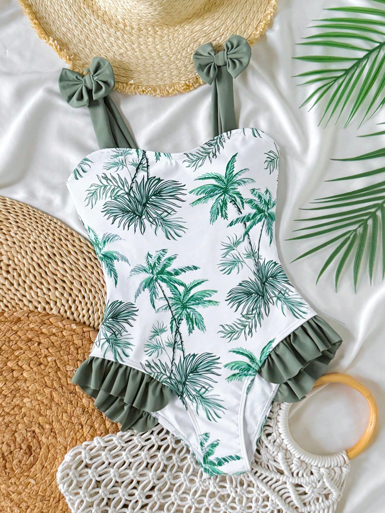 Girls' multicolor one-piece swimsuit with floral plant print, bow detail, asymmetrical ruffle accent, strap neckline, and lined body for beach vacations.