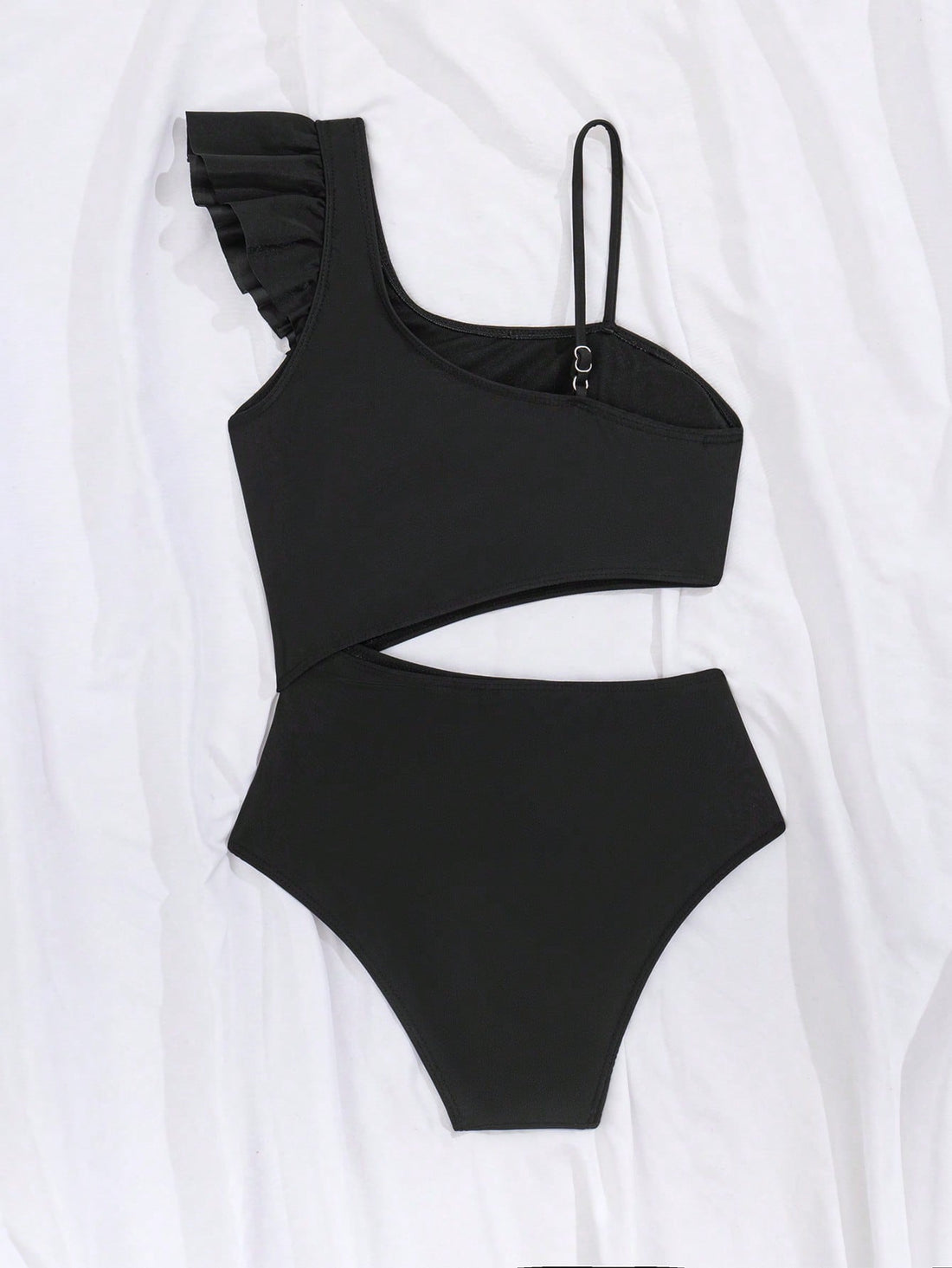 Tween girl one-piece swimsuit in brown polka dot geometric print with asymmetrical neckline, ruffle detail, cut-out design, and fitted mid-waist swim bottom.
