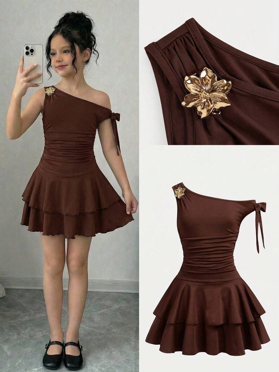 Tween girl wearing an apricot asymmetrical tiered sleeveless party dress with an A-line silhouette.