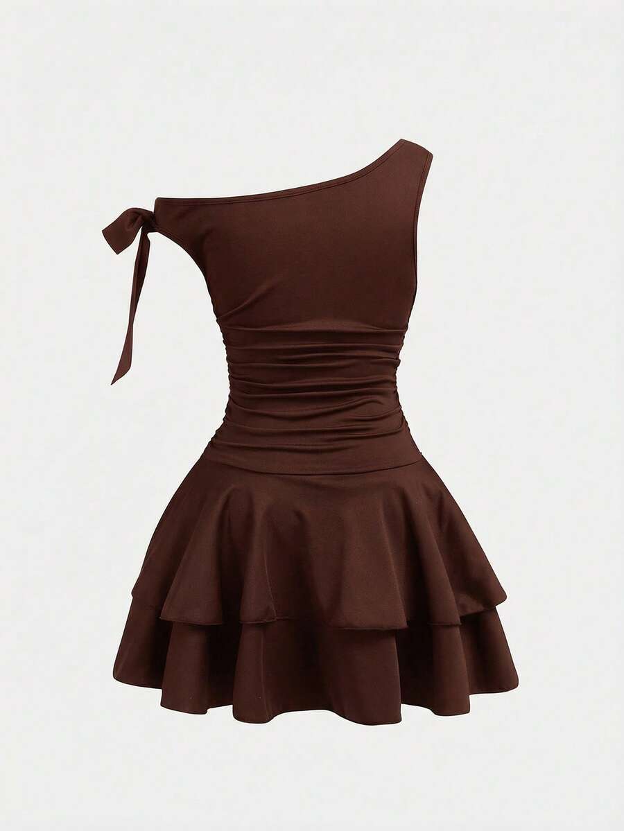 Tween girl wearing an apricot asymmetrical tiered sleeveless party dress with an A-line silhouette.