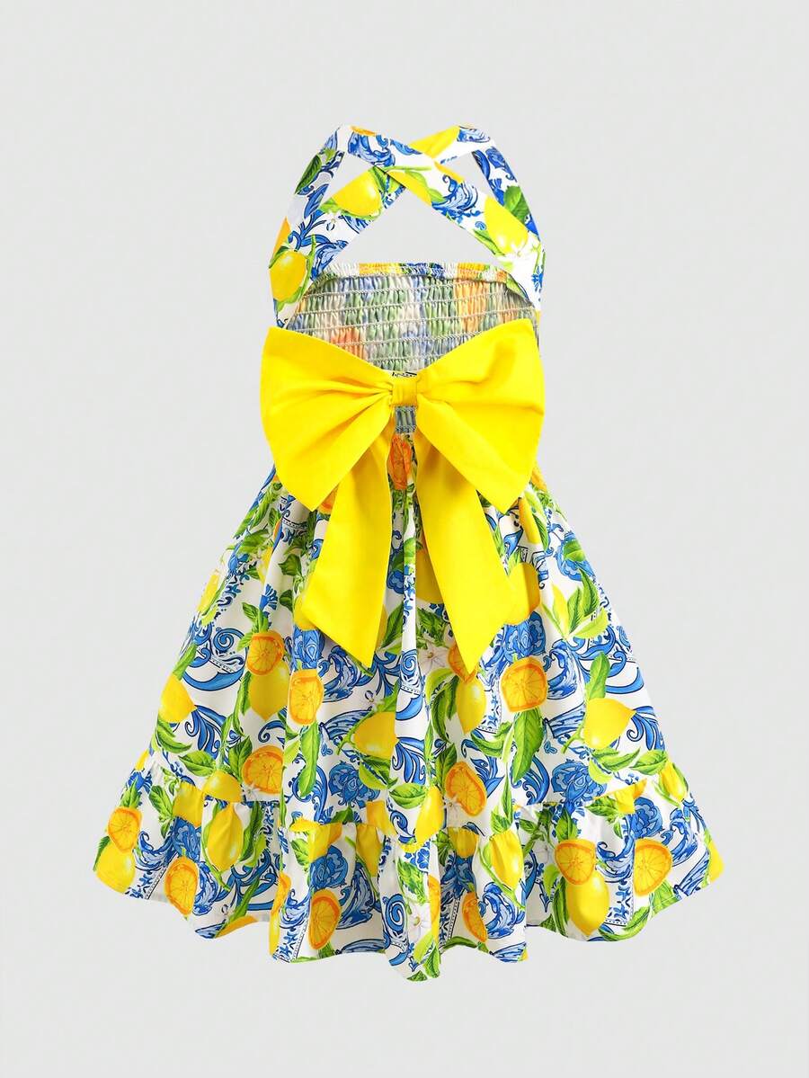 Pink sleeveless tween girls vacation dress with all-over fruit and vegetable print, strap neckline, belted high waist, cut-out detail, and flared ruffle hem.