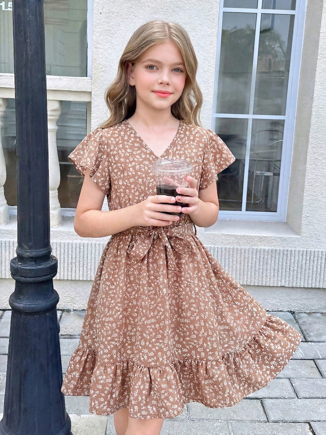 Tween girl wearing a black ditsy floral A-line short dress with V-neckline and flounce short sleeves.