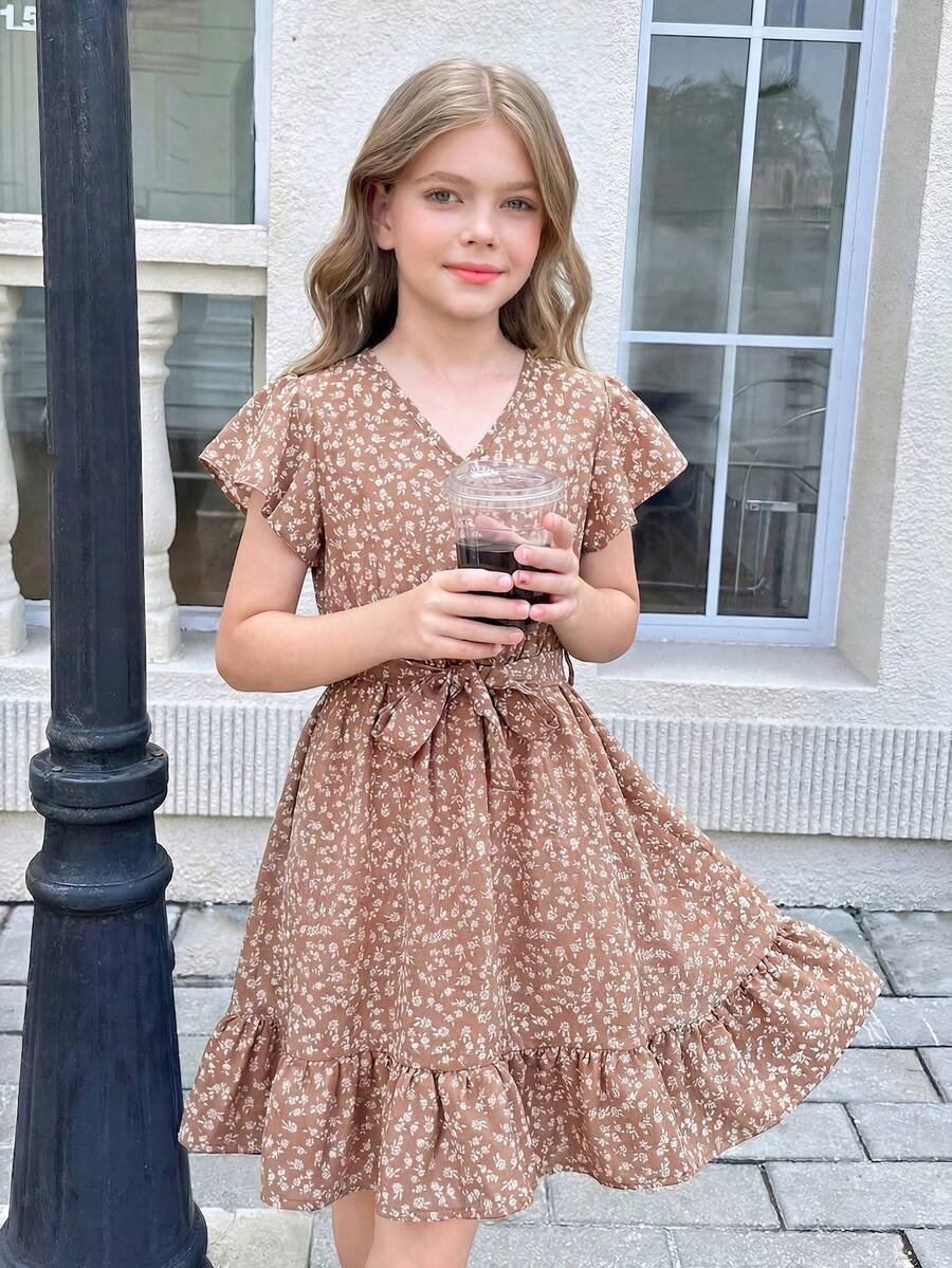 Tween girl wearing a black ditsy floral A-line short dress with V-neckline and flounce short sleeves.
