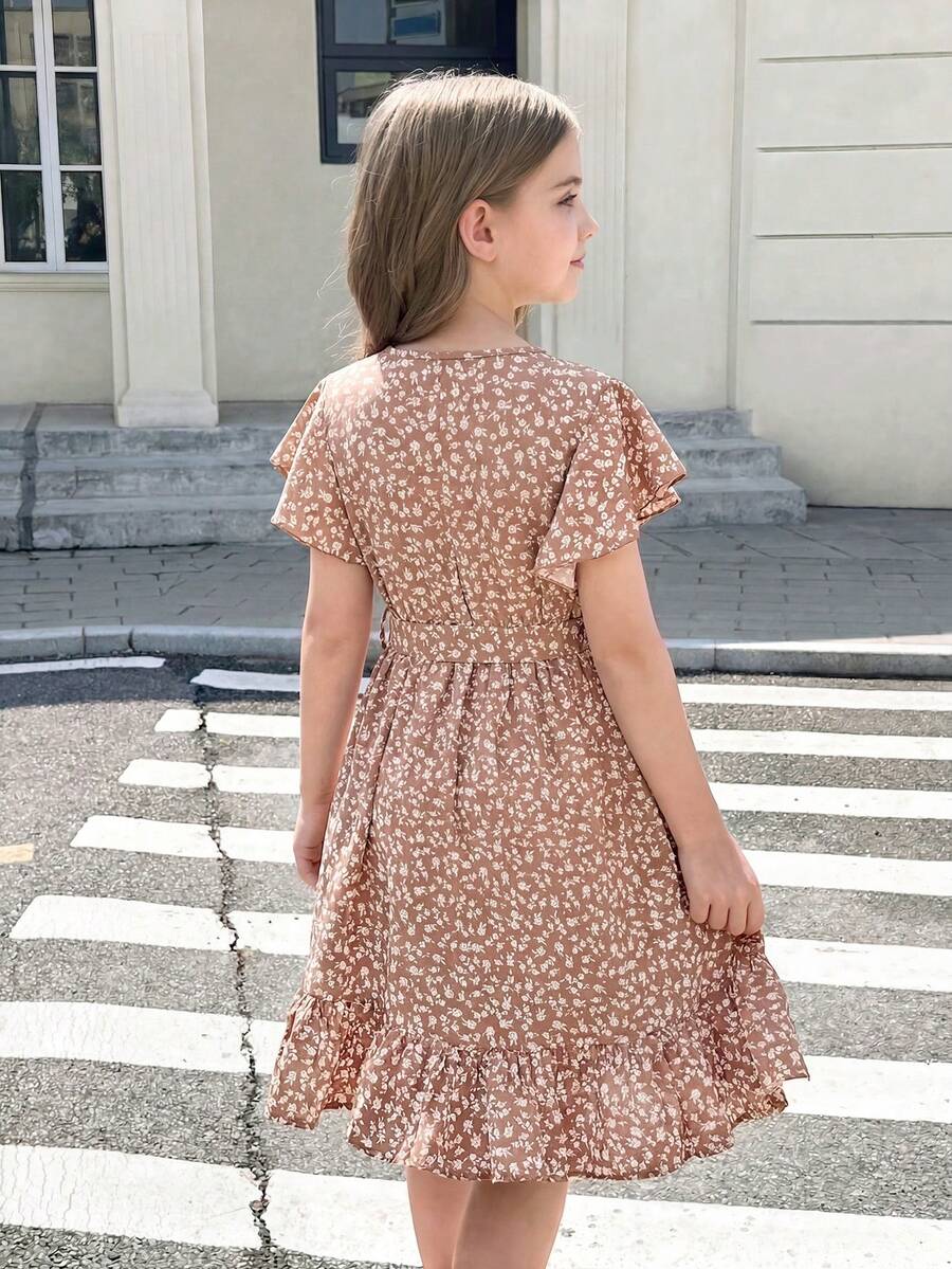 Tween girl wearing a black ditsy floral A-line short dress with V-neckline and flounce short sleeves.