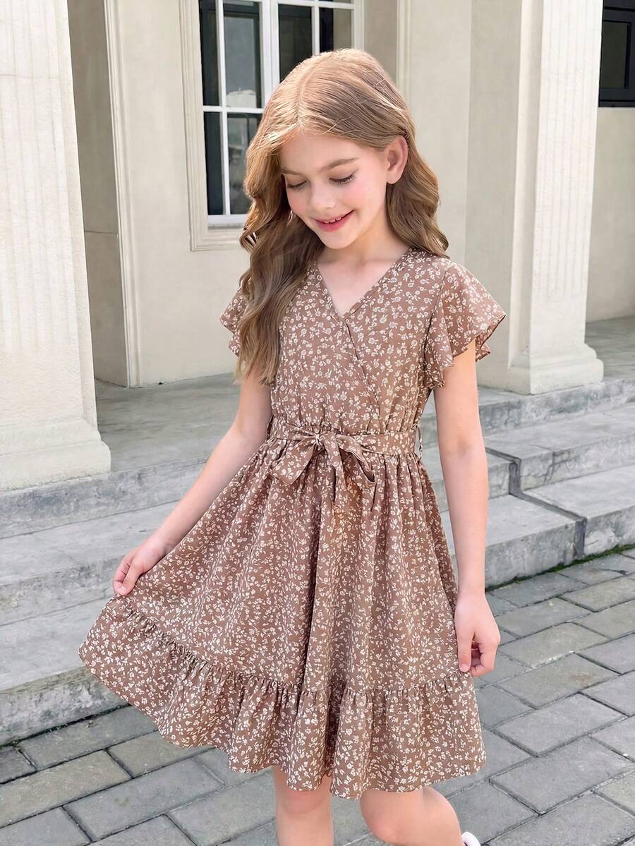 Tween girl wearing a black ditsy floral A-line short dress with V-neckline and flounce short sleeves.