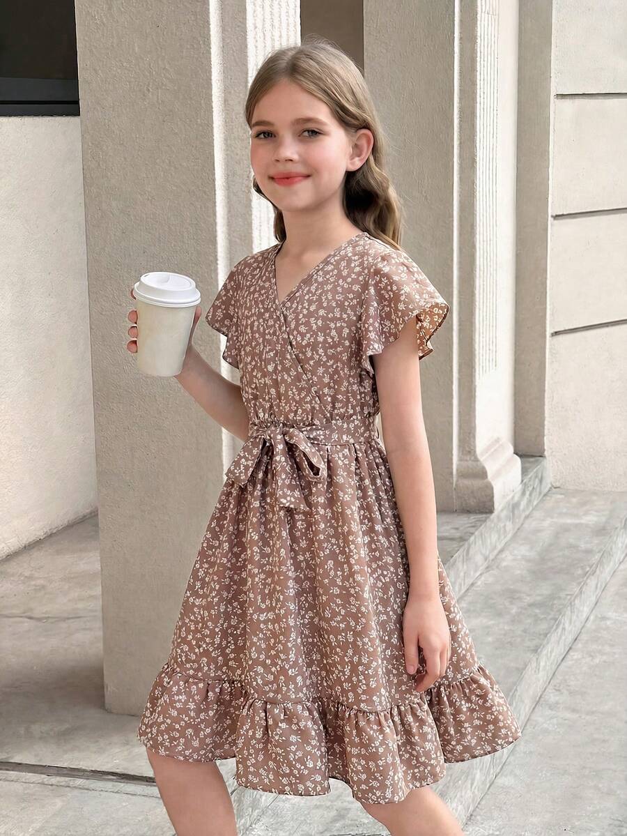 Tween girl wearing a black ditsy floral A-line short dress with V-neckline and flounce short sleeves.