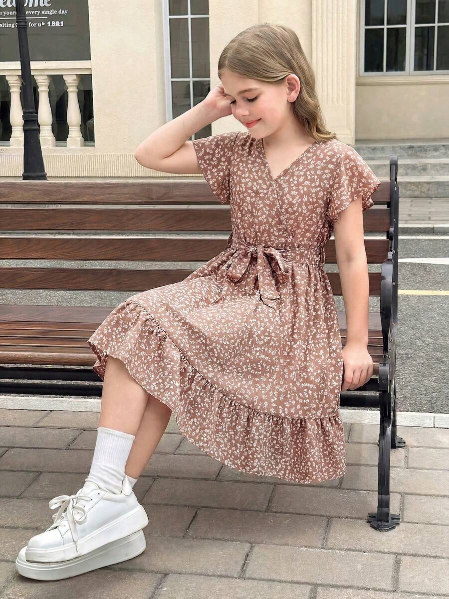 Tween girl wearing a black ditsy floral A-line short dress with V-neckline and flounce short sleeves.