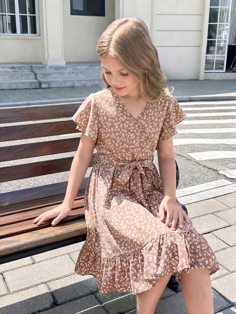 Tween girl wearing a black ditsy floral A-line short dress with V-neckline and flounce short sleeves.