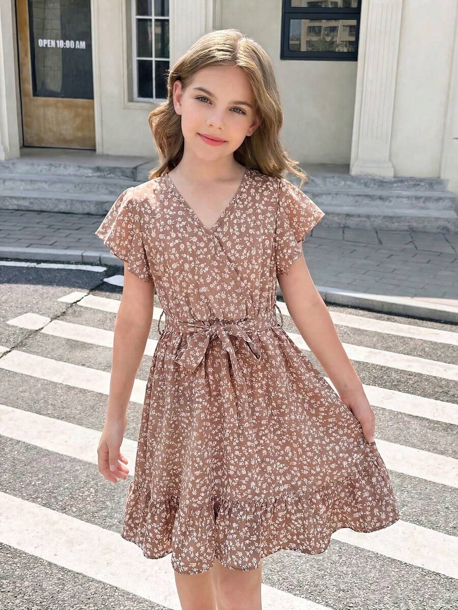 Tween girl wearing a black ditsy floral A-line short dress with V-neckline and flounce short sleeves.