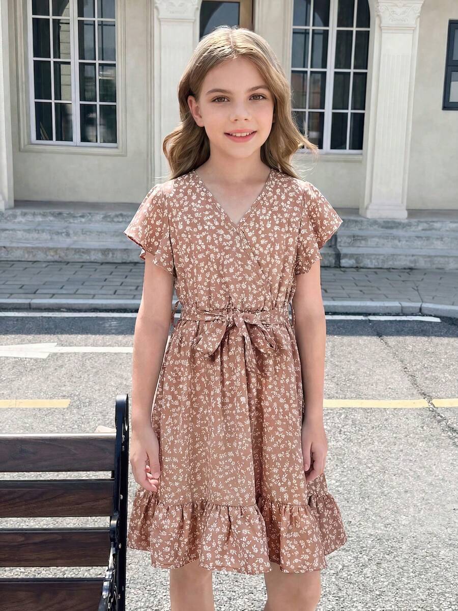 Tween girl wearing a black ditsy floral A-line short dress with V-neckline and flounce short sleeves.