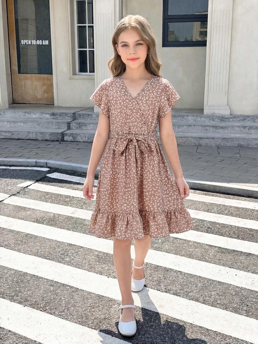 Tween girl wearing a black ditsy floral A-line short dress with V-neckline and flounce short sleeves.