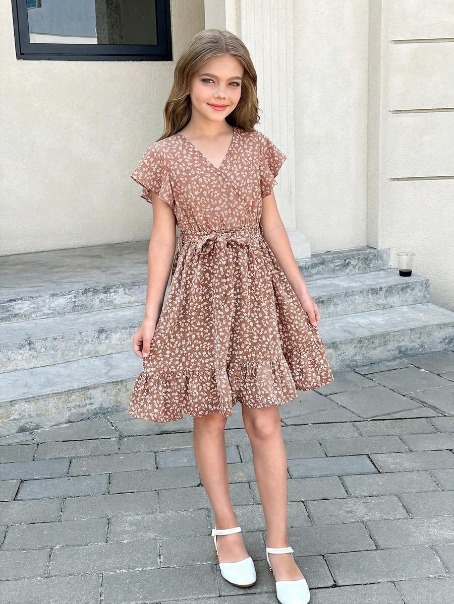 Tween girl wearing a black ditsy floral A-line short dress with V-neckline and flounce short sleeves.