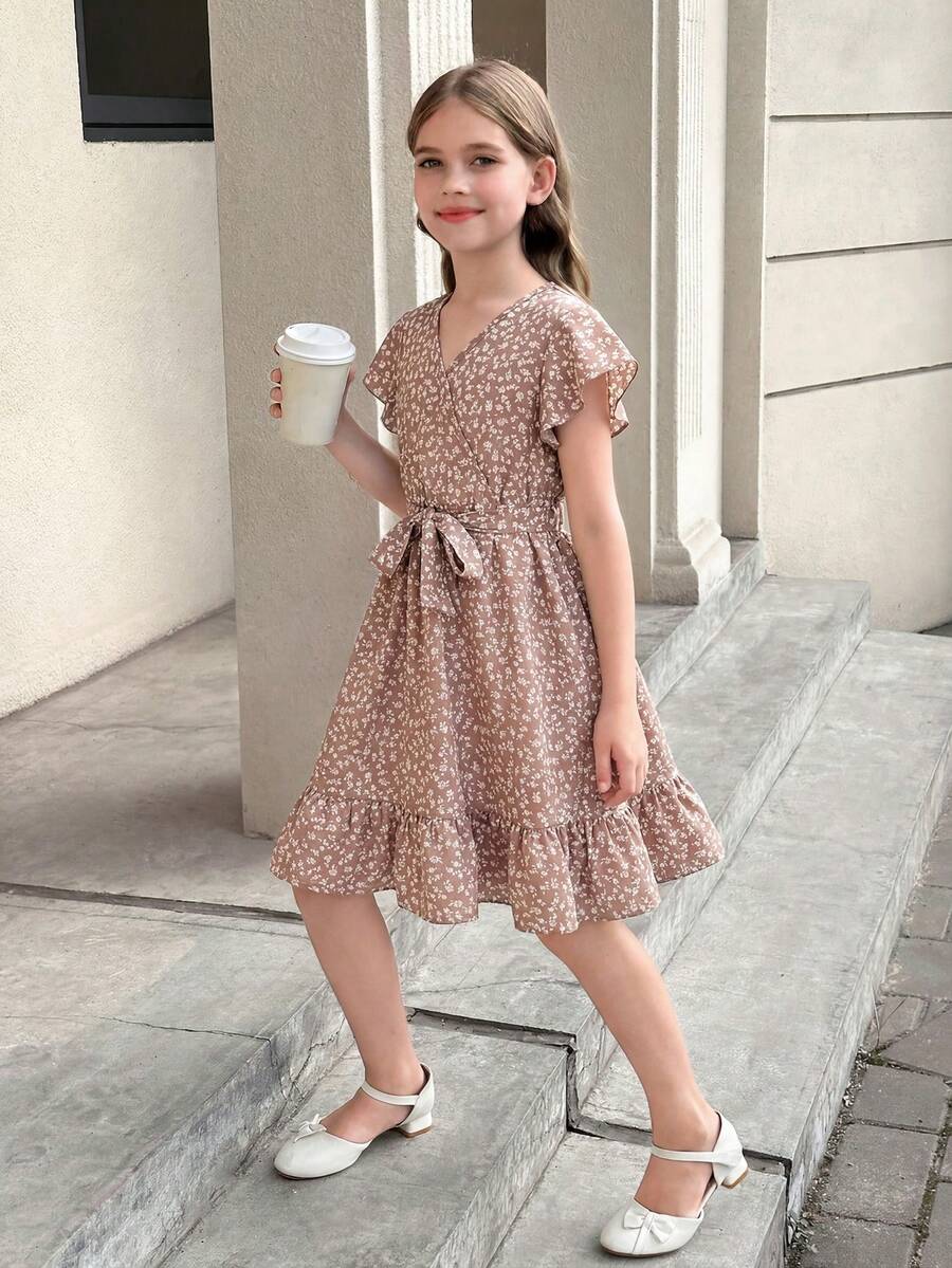 Tween girl wearing a black ditsy floral A-line short dress with V-neckline and flounce short sleeves.