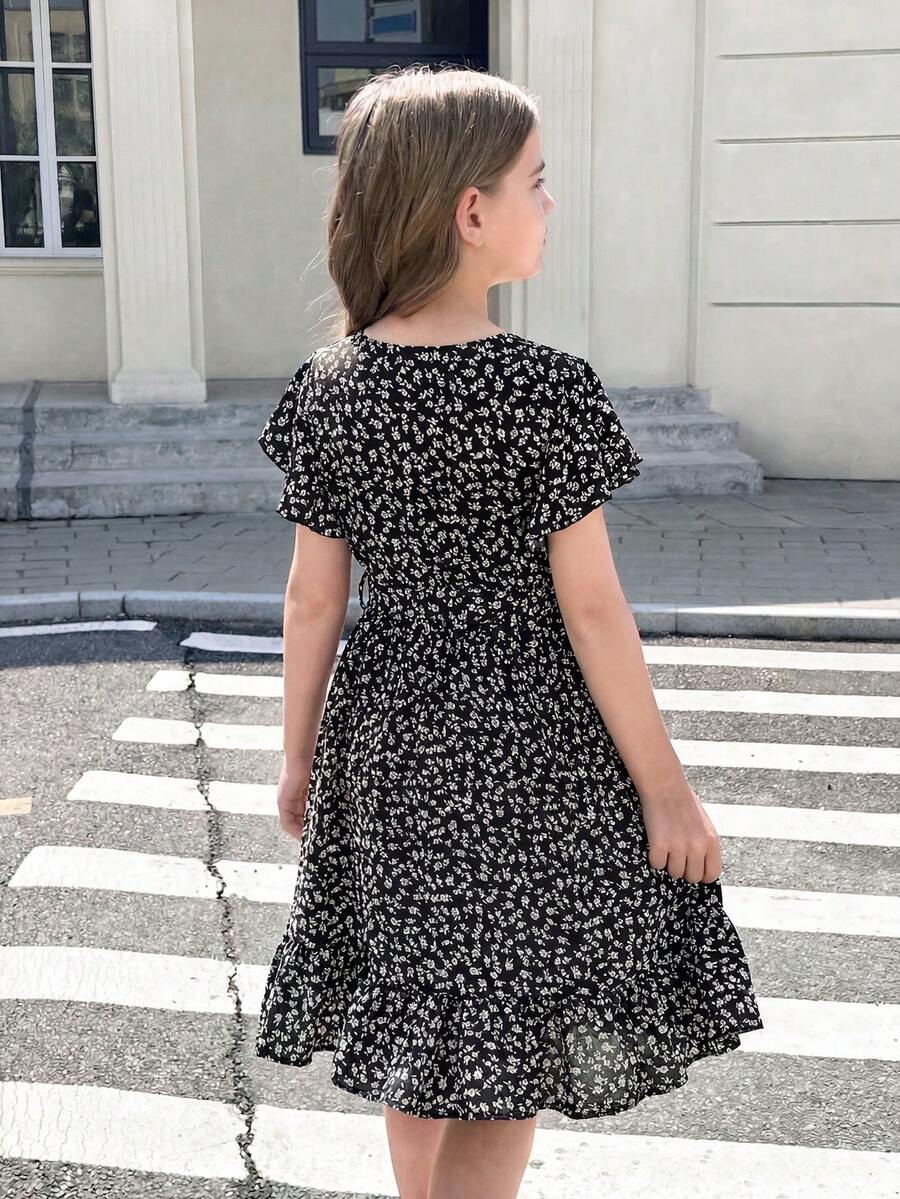 Tween girl wearing a black ditsy floral A-line short dress with V-neckline and flounce short sleeves.