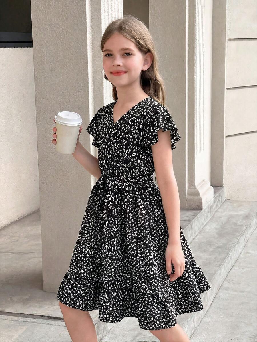 Tween girl wearing a black ditsy floral A-line short dress with V-neckline and flounce short sleeves.