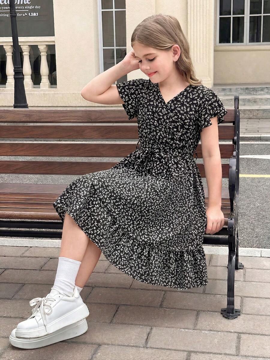 Tween girl wearing a black ditsy floral A-line short dress with V-neckline and flounce short sleeves.