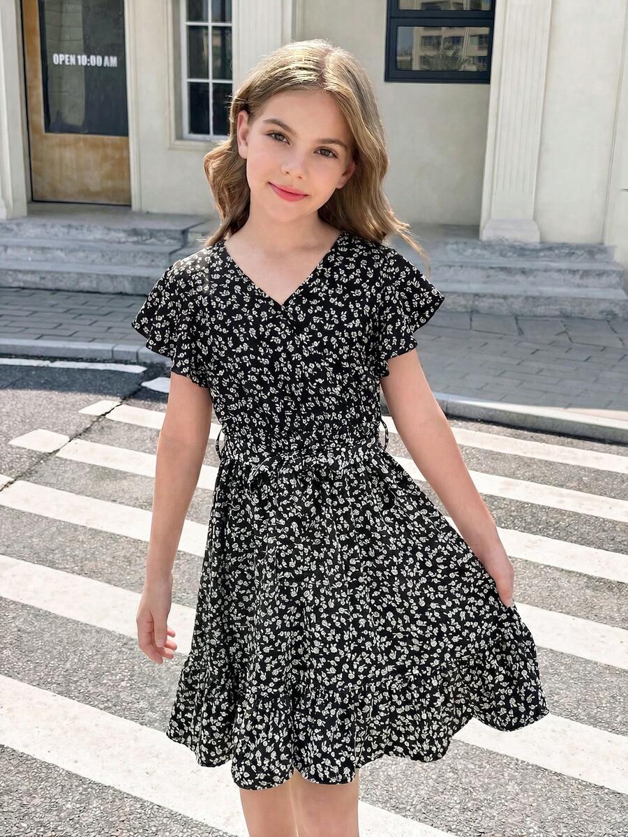 Tween girl wearing a black ditsy floral A-line short dress with V-neckline and flounce short sleeves.
