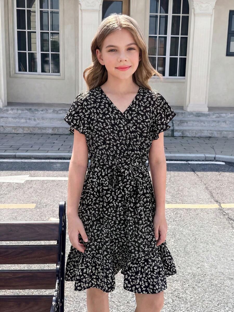 Tween girl wearing a black ditsy floral A-line short dress with V-neckline and flounce short sleeves.