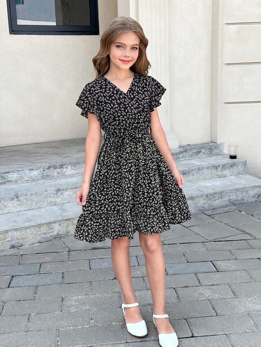 Tween girl wearing a black ditsy floral A-line short dress with V-neckline and flounce short sleeves.