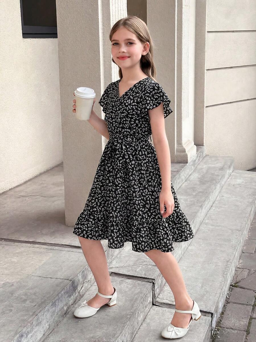 Tween girl wearing a black ditsy floral A-line short dress with V-neckline and flounce short sleeves.