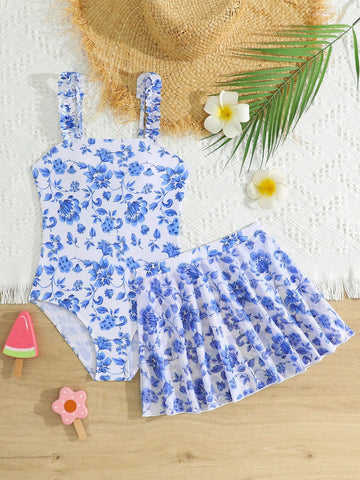 Blue tween girls one-piece swimsuit with tropical plant print, spaghetti straps, ruffle detail, and skirt-style mid-waist bottom for beach and pool wear.