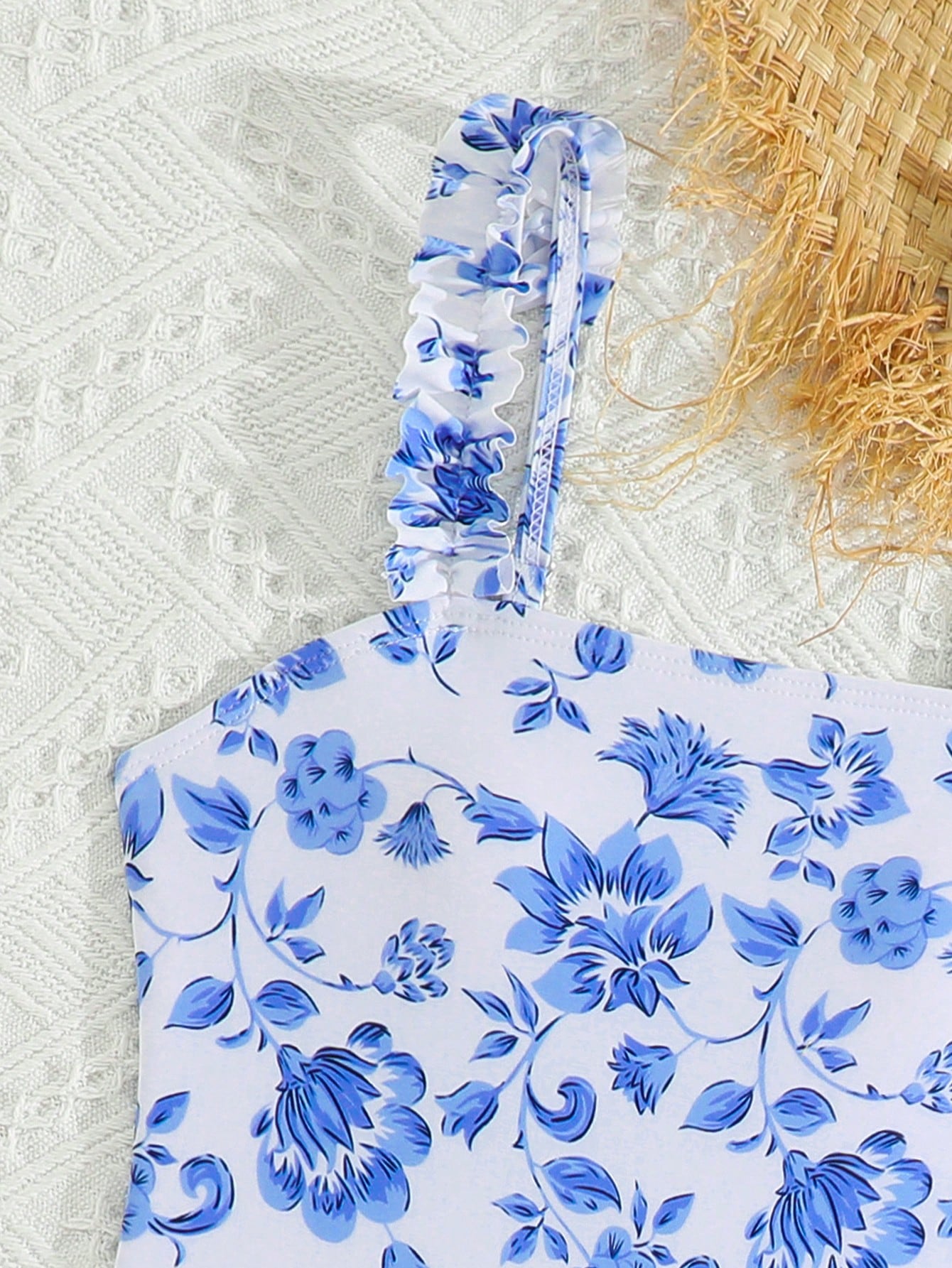Blue tween girls one-piece swimsuit with tropical plant print, spaghetti straps, ruffle detail, and skirt-style mid-waist bottom for beach and pool wear.