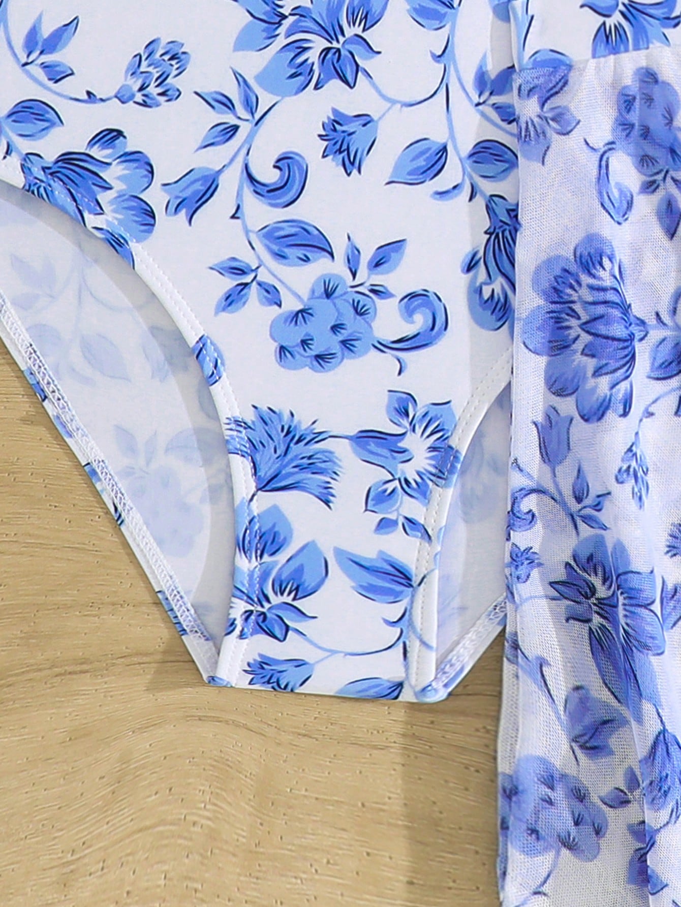 Blue tween girls one-piece swimsuit with tropical plant print, spaghetti straps, ruffle detail, and skirt-style mid-waist bottom for beach and pool wear.