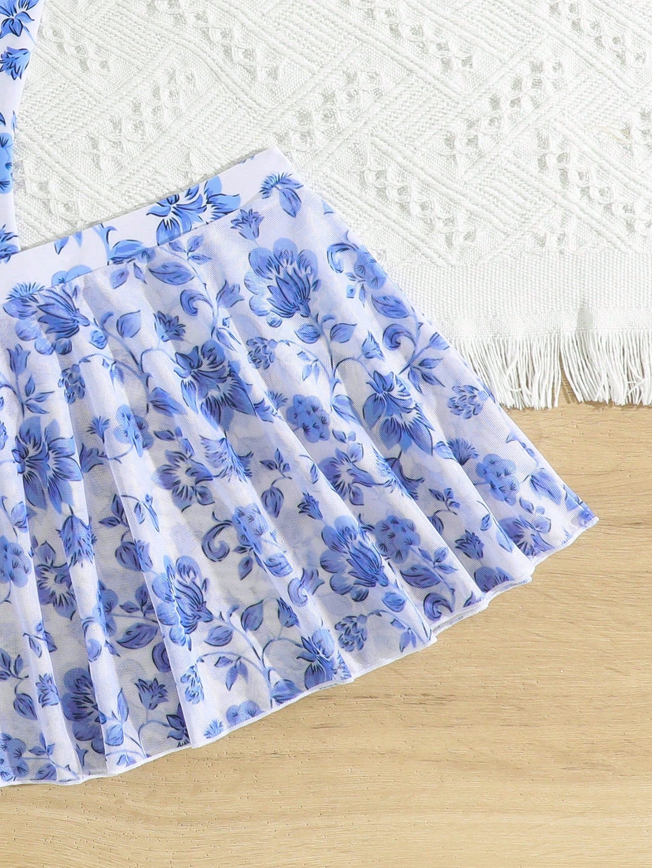 Blue tween girls one-piece swimsuit with tropical plant print, spaghetti straps, ruffle detail, and skirt-style mid-waist bottom for beach and pool wear.