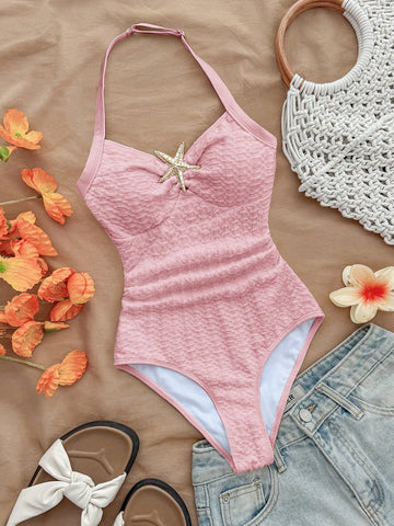 Pink textured halter one-piece swimsuit for tween girls with V-neck, tie strap, starfish and shell tassel accents, and lined body.