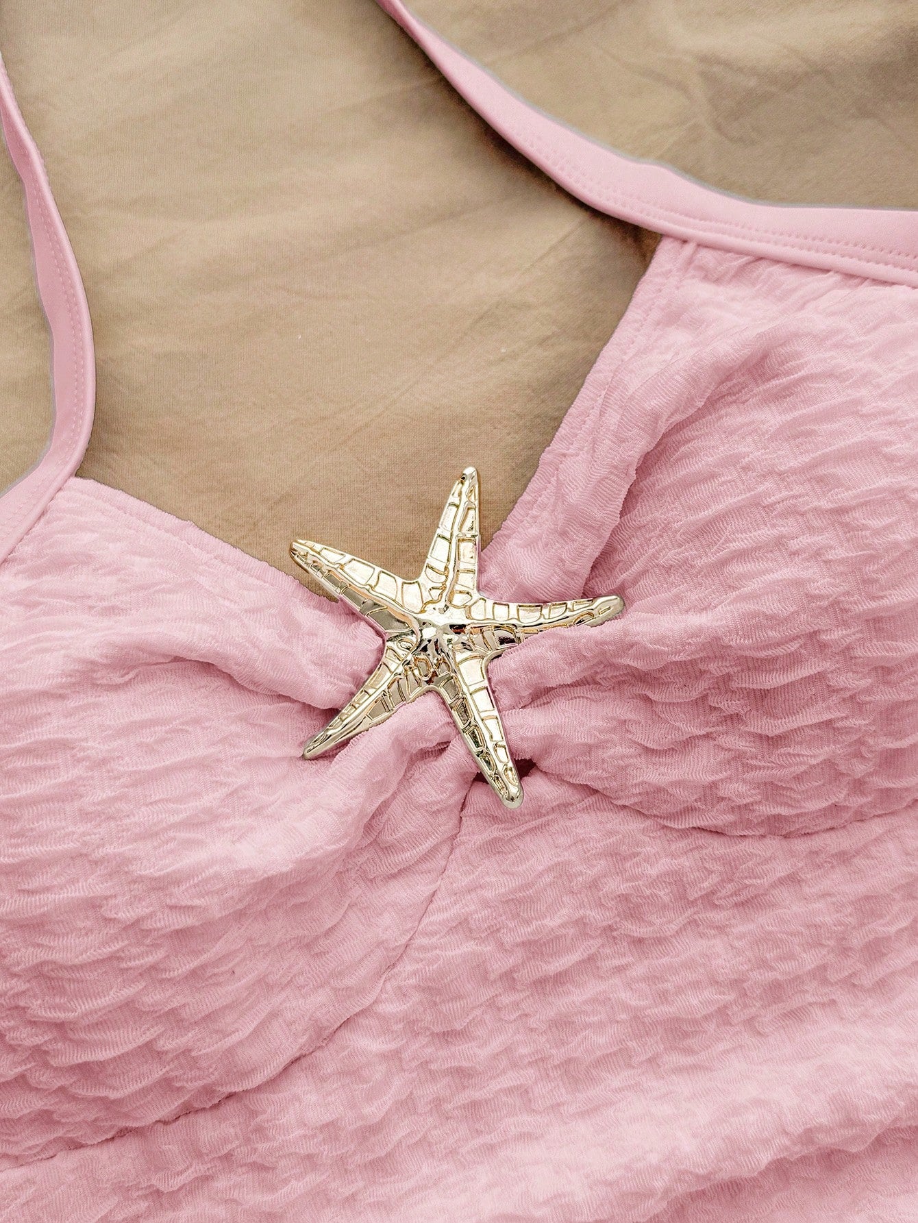 Pink textured halter one-piece swimsuit for tween girls with V-neck, tie strap, starfish and shell tassel accents, and lined body.