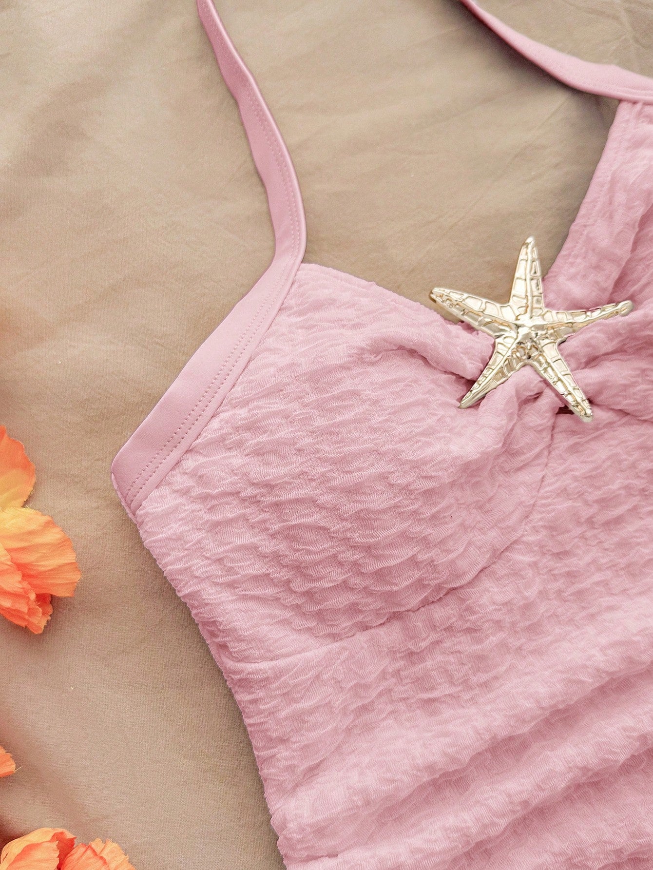 Pink textured halter one-piece swimsuit for tween girls with V-neck, tie strap, starfish and shell tassel accents, and lined body.