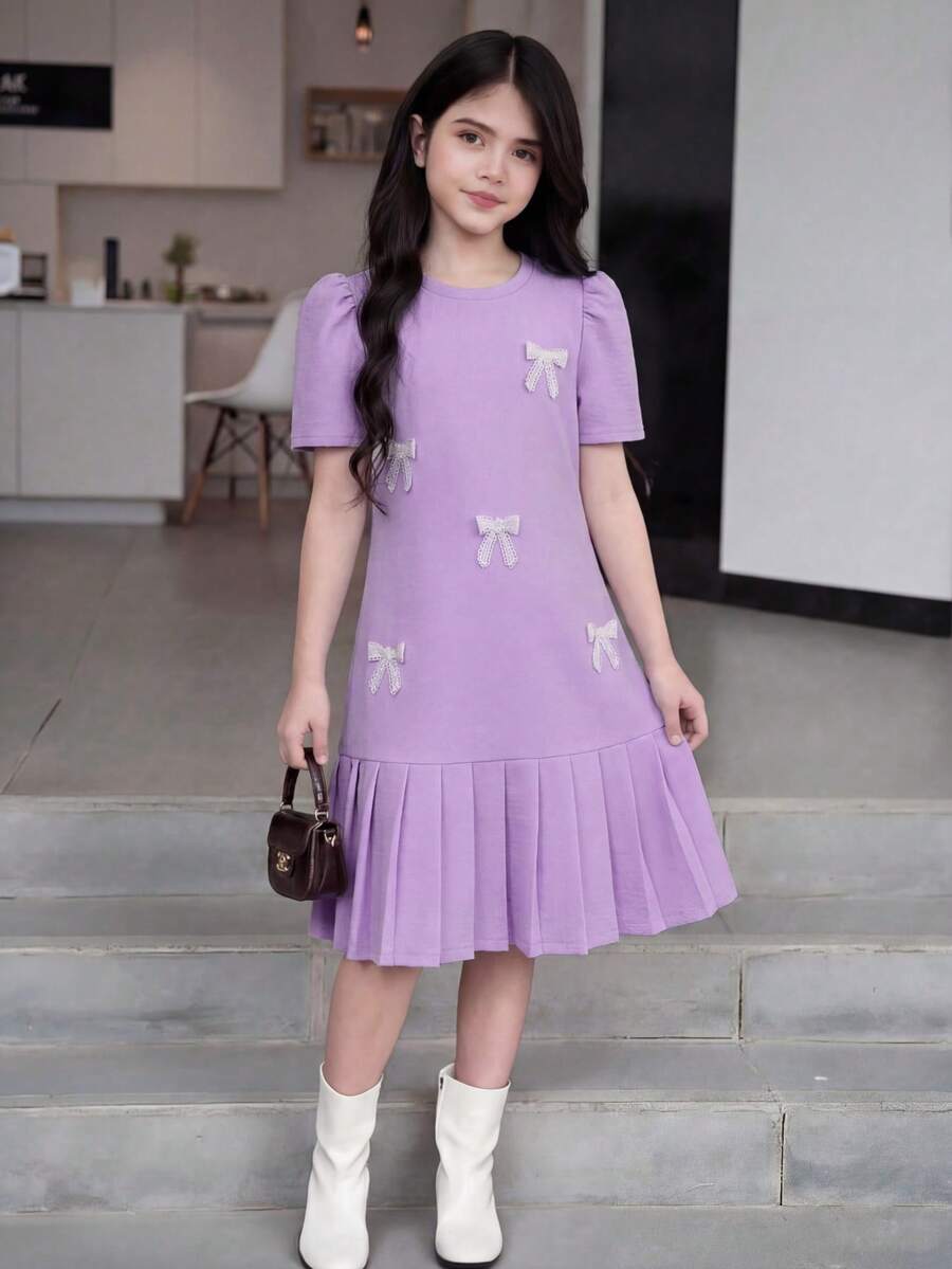 Tween girls apricot short-sleeve pleated smock dress with 3D bow decor and round neckline.