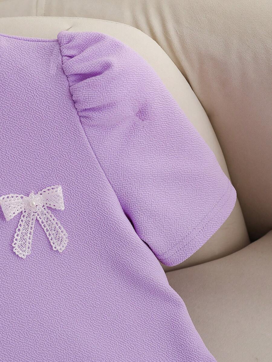Tween girls apricot short-sleeve pleated smock dress with 3D bow decor and round neckline.