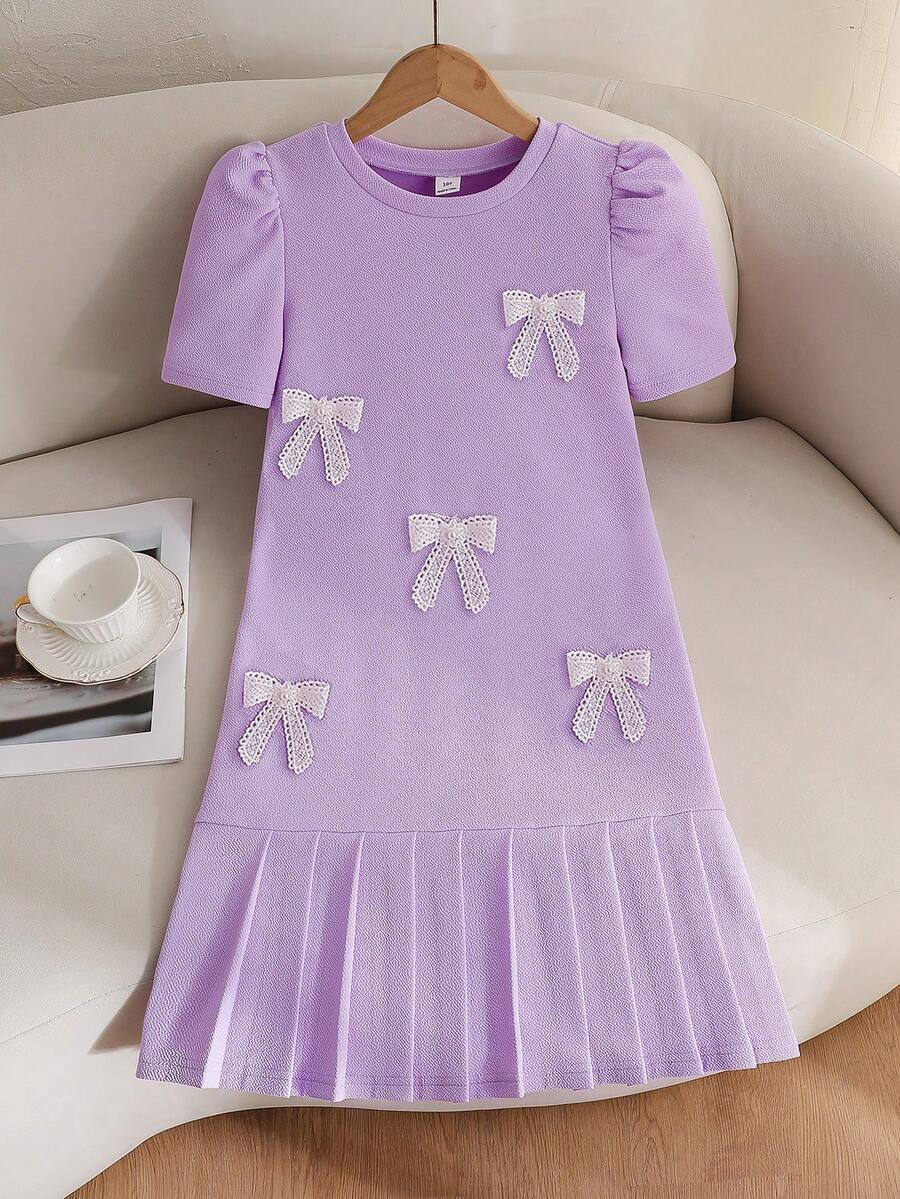 Tween girls apricot short-sleeve pleated smock dress with 3D bow decor and round neckline.