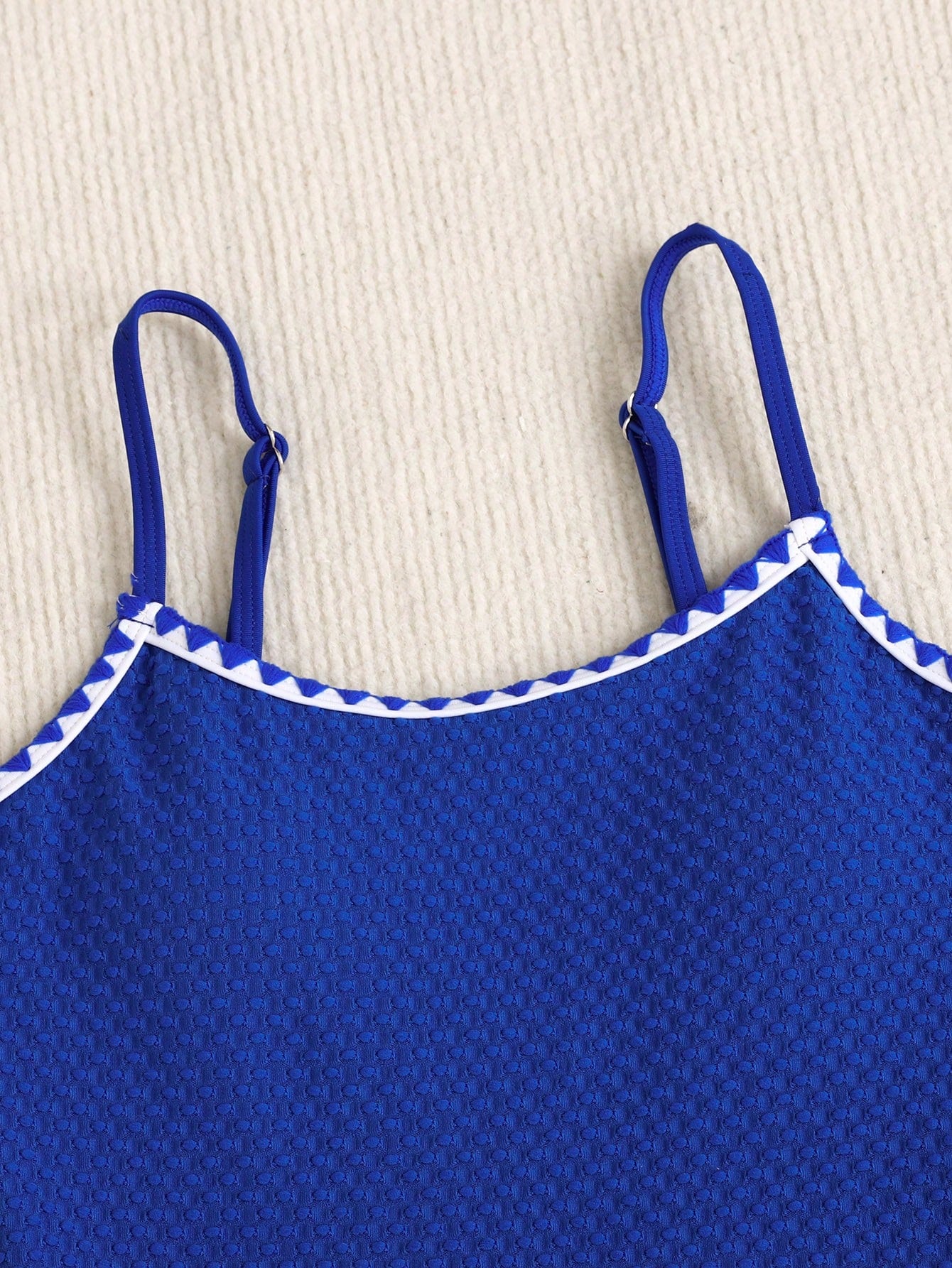 Blue colorblock one-piece swimsuit for tween girls with all-over print, contrast piping, spaghetti straps, and lined high-stretch fabric for beach or pool wear.