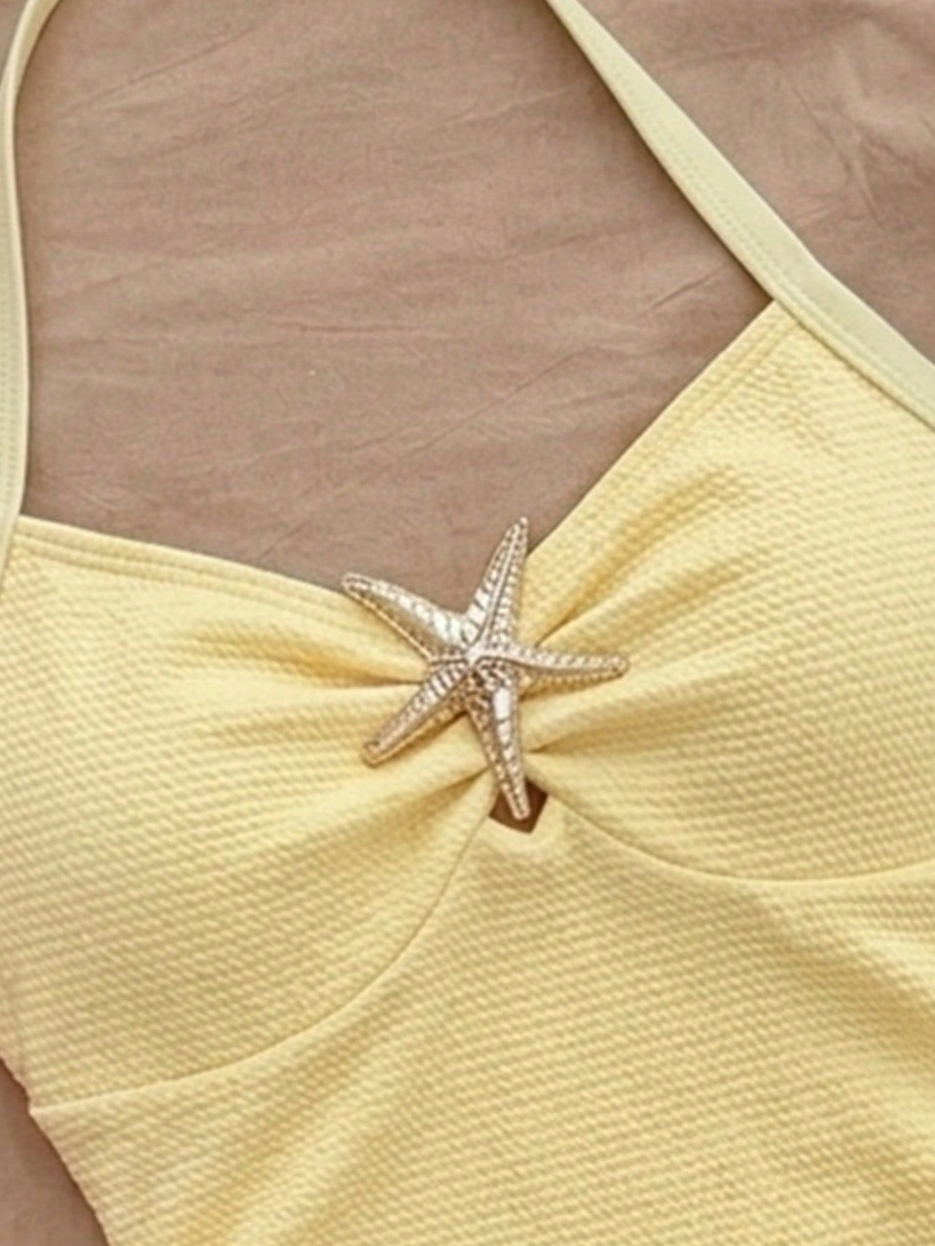 Pink textured halter one-piece swimsuit for tween girls with V-neck, tie strap, starfish and shell tassel accents, and lined body.