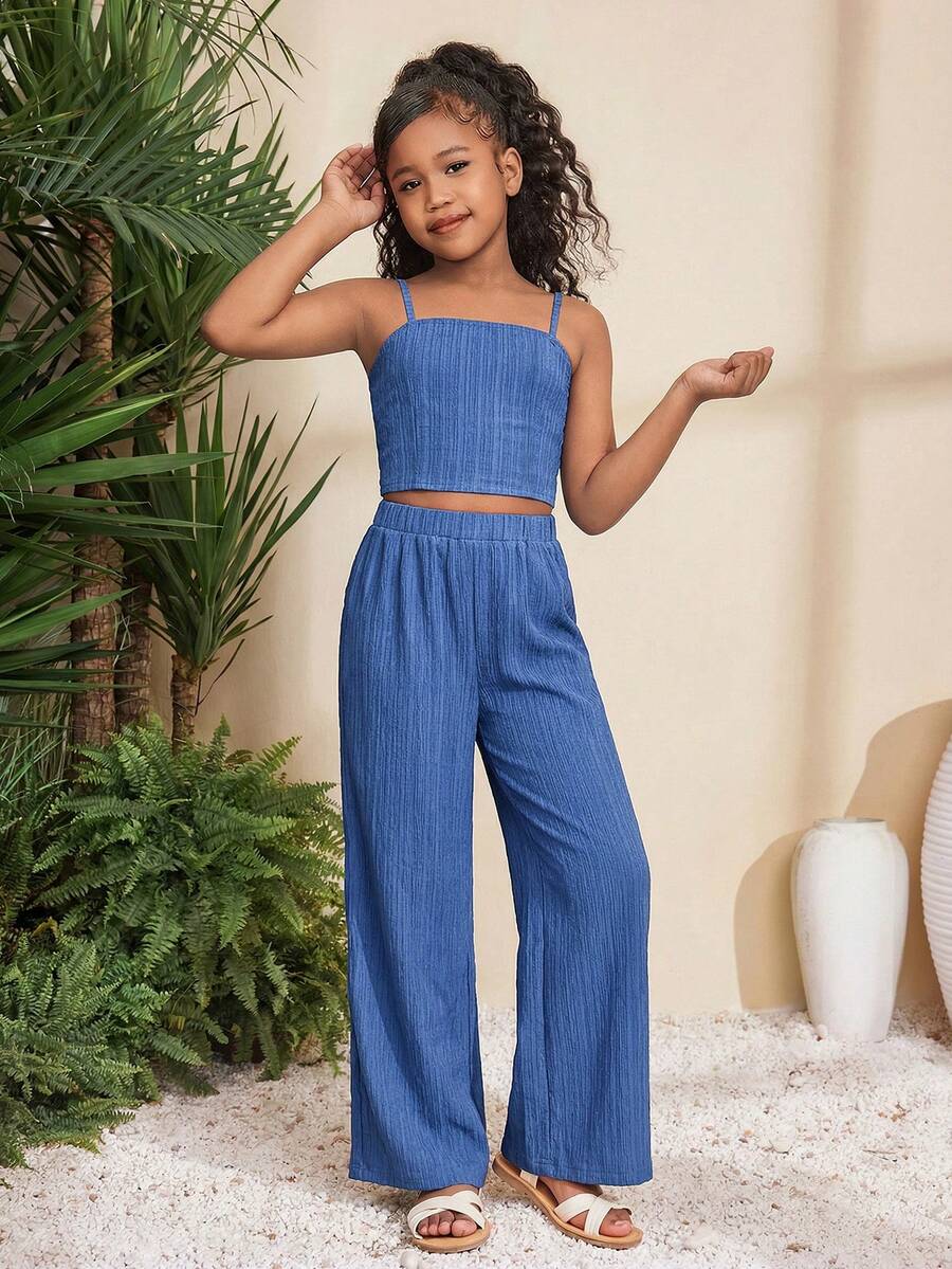 Tween girl wearing a black sleeveless spaghetti strap camisole top with 3D bow decor and matching leopard print wide leg long pants.