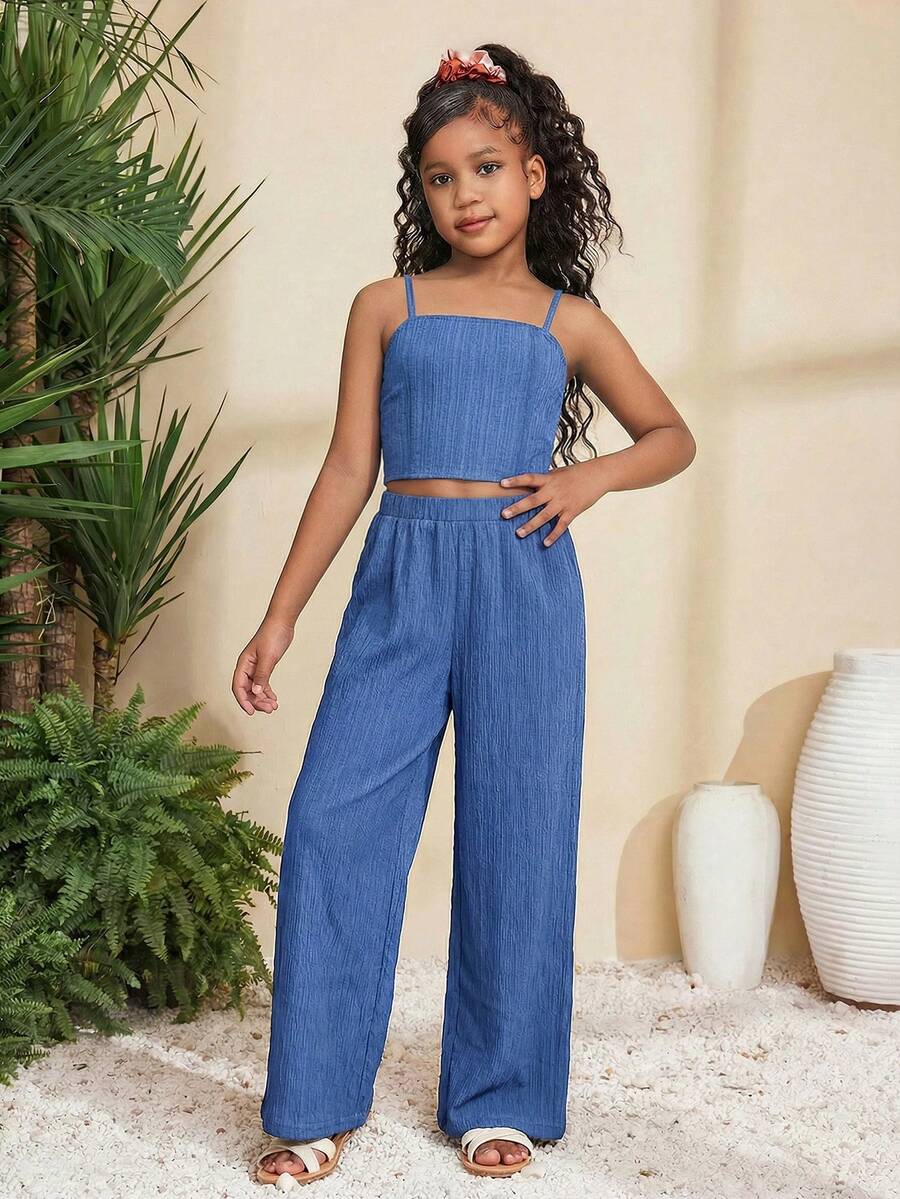 Tween girl wearing a black sleeveless spaghetti strap camisole top with 3D bow decor and matching leopard print wide leg long pants.