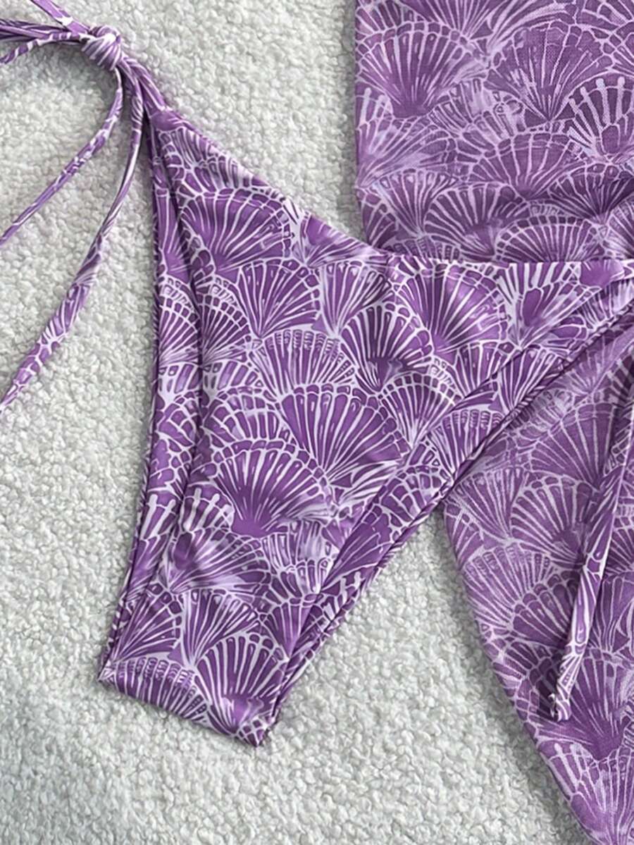 Women's 3-piece blue tropical shell print bikini set featuring a halter bralette top, low-waist tie-side bottom, and a matching sheer mesh cover-up skirt.