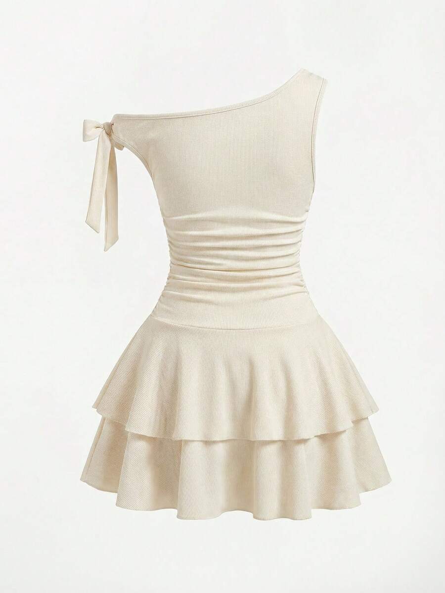 Tween girl wearing an apricot asymmetrical tiered sleeveless party dress with an A-line silhouette.