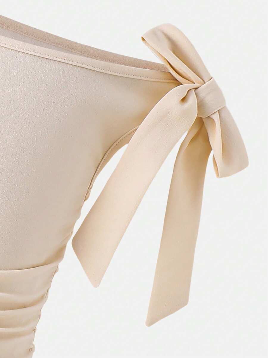 Tween girl wearing an apricot asymmetric skater dress with ruffle and applique details for party and formal occasions.