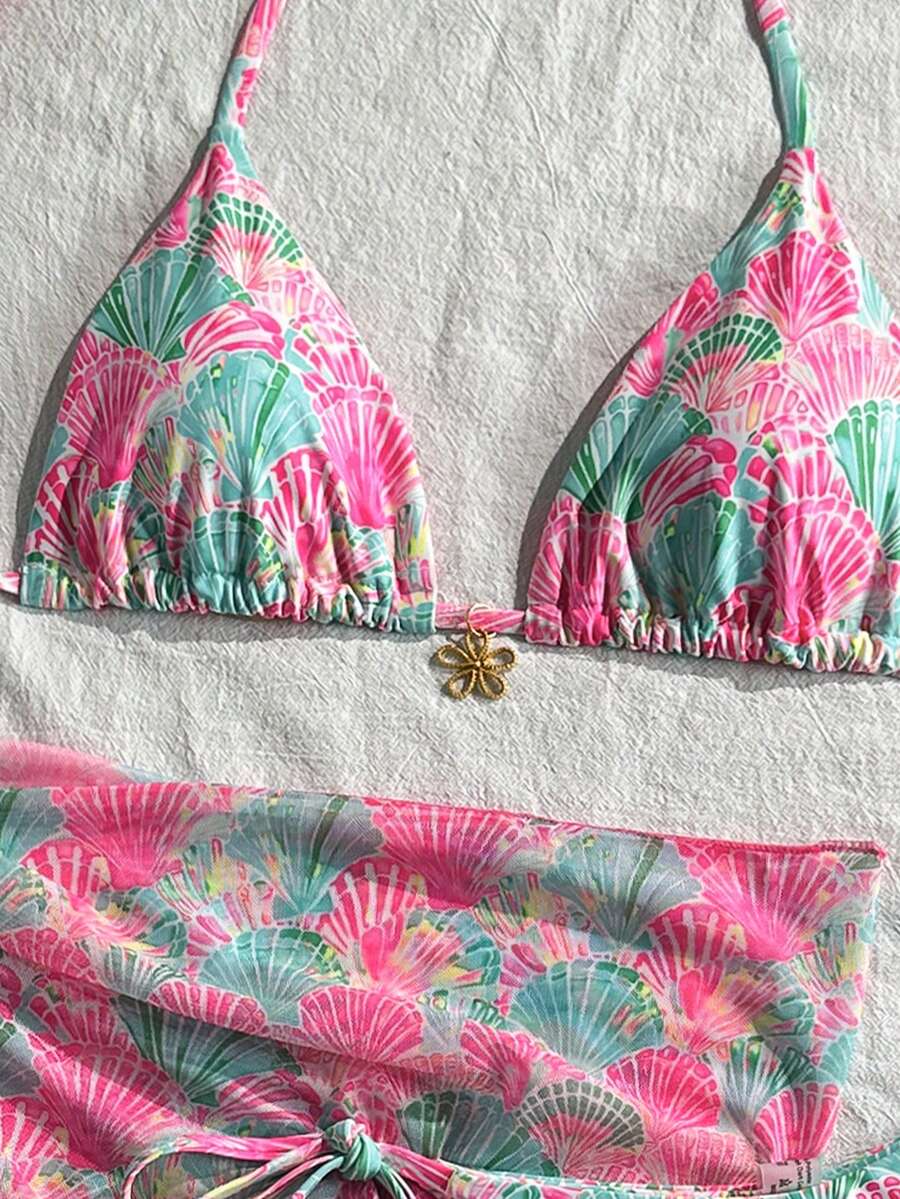 Women's 3-piece blue tropical shell print bikini set featuring a halter bralette top, low-waist tie-side bottom, and a matching sheer mesh cover-up skirt.