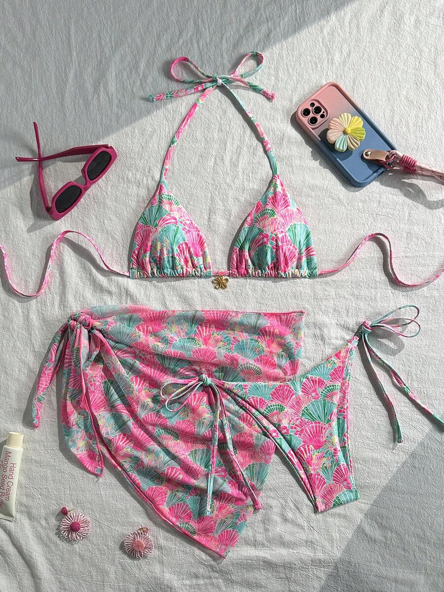 Women's 3-piece blue tropical shell print bikini set featuring a halter bralette top, low-waist tie-side bottom, and a matching sheer mesh cover-up skirt.